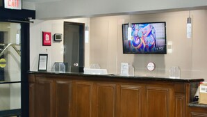 Un'area reception con scrivania in legno, televisore a parete e pavimento tappezzato.
