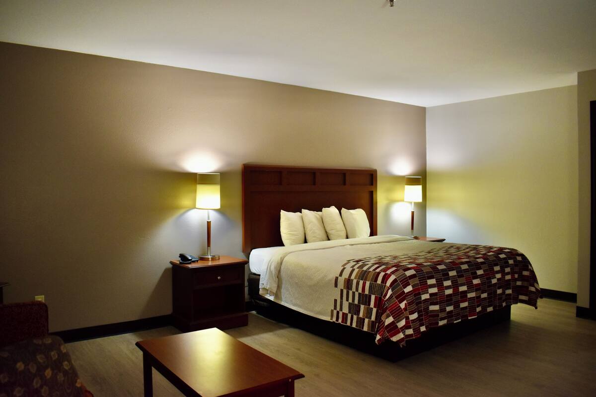 A hotel room with a bed, bedside tables, lamps, and a small table.
