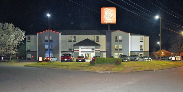 A Red Roof Inn with a modern building facade, multiple parking spaces, and a well-lit entrance.