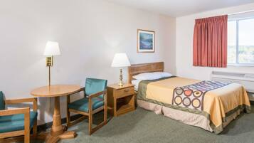 A hotel room with a bed, two chairs, a small table, a nightstand, a lamp, a window with curtains, and a painting on the wall.