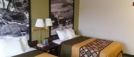 Quarto de hotel com duas camas, uma mesa de cabeceira, um abajur e um quadro grande com uma paisagem na parede.
