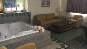 A hotel room with a large bathtub, a sofa, a chair, a small table, and a lamp. - Super 8 by Wyndham West Middlesex/Sharon Area (West Middlesex)
