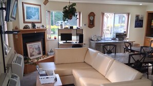 A living room with a sofa, a fireplace, a television, and a kitchen area with a dining table and chairs. - Super 8 by Wyndham West Middlesex/Sharon Area (West Middlesex)