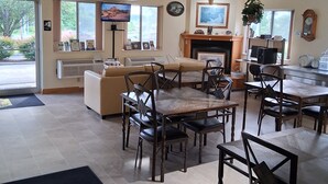 A spacious room with a dining area, a sofa, a fireplace, and a television. - Super 8 by Wyndham West Middlesex/Sharon Area (West Middlesex)