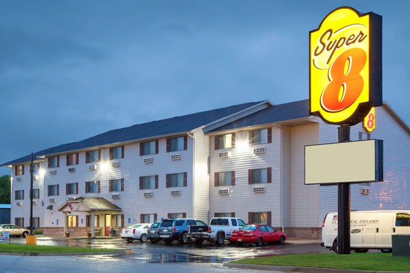 Un motel Super 8 con una fila de coches aparcados y un cartel iluminado grande.