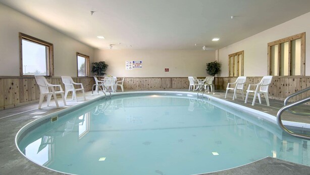 Una piscina interior con sillas blancas alrededor, paneles de madera en las paredes y un letrero en la pared.