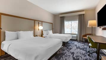 Une chambre d’hôtel avec deux lits, un bureau, une chaise, une télévision et une fenêtre avec des rideaux.