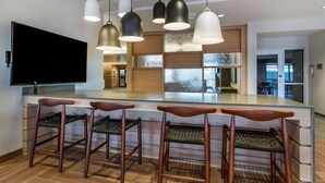 A modern kitchen with a large island, bar stools, pendant lighting, and a flat-screen TV. - Fairfield by Marriott Inn & Suites Sandusky (Sandusky)