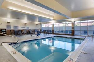 Una piscina interior con agua cristalina, rodeada de sillones y mesas.