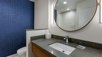 A bathroom with a white toilet, a marble sink with a mirror, and a blue patterned wall.