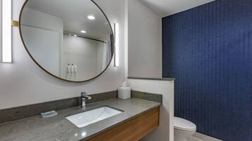 A modern bathroom with a large mirror, a sink, and a toilet.