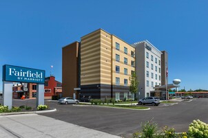 Un hotel Fairfield by Marriott con diseño moderno, un estacionamiento y un cielo azul despejado.