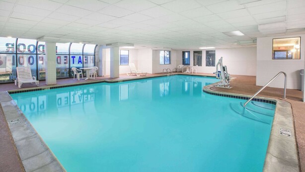 An indoor swimming pool with clear water, surrounded by lounge chairs and a sunbed. - Super 8 by Wyndham Garland North Dallas Area (Garland)