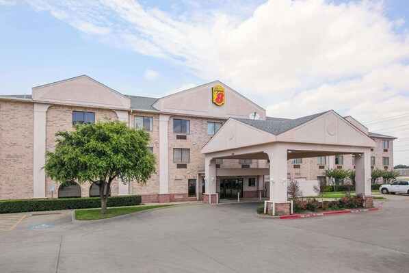 Un hotel con un llamativo logotipo de 'Super 8', fachada de ladrillo y una zona de acceso cubierta.