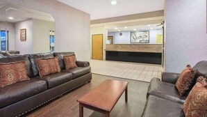 A lobby with leather sofas, a wooden coffee table, and a reception desk. - Super 8 by Wyndham Garland North Dallas Area (Garland)