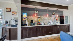 A modern kitchen with dark cabinets, a microwave, and a coffee machine.