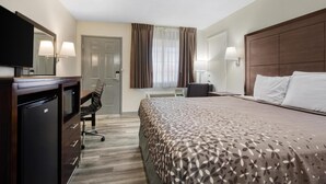 A hotel room with a bed, a desk with a chair, a television, and a wardrobe.