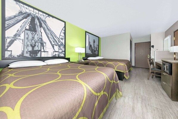 A hotel room with two beds, a desk, a chair, and a door leading to another room.