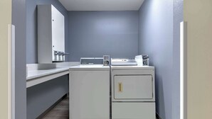 A compact laundry room with a washing machine, dryer, and a small countertop with a sink. - Super 8 by Wyndham Waxahachie TX (Waxahachie)