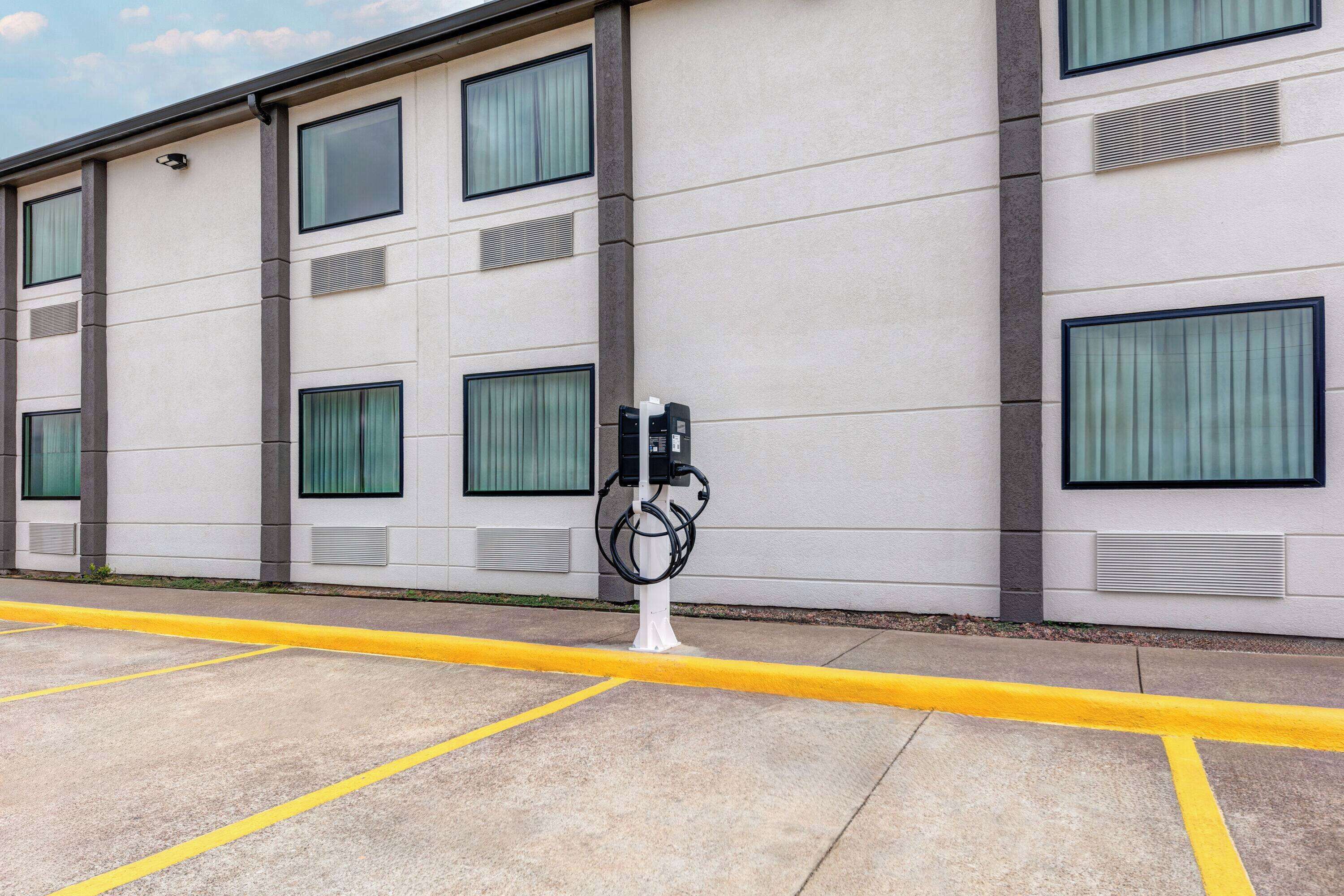 A building with multiple windows and a parking lot with yellow lines.