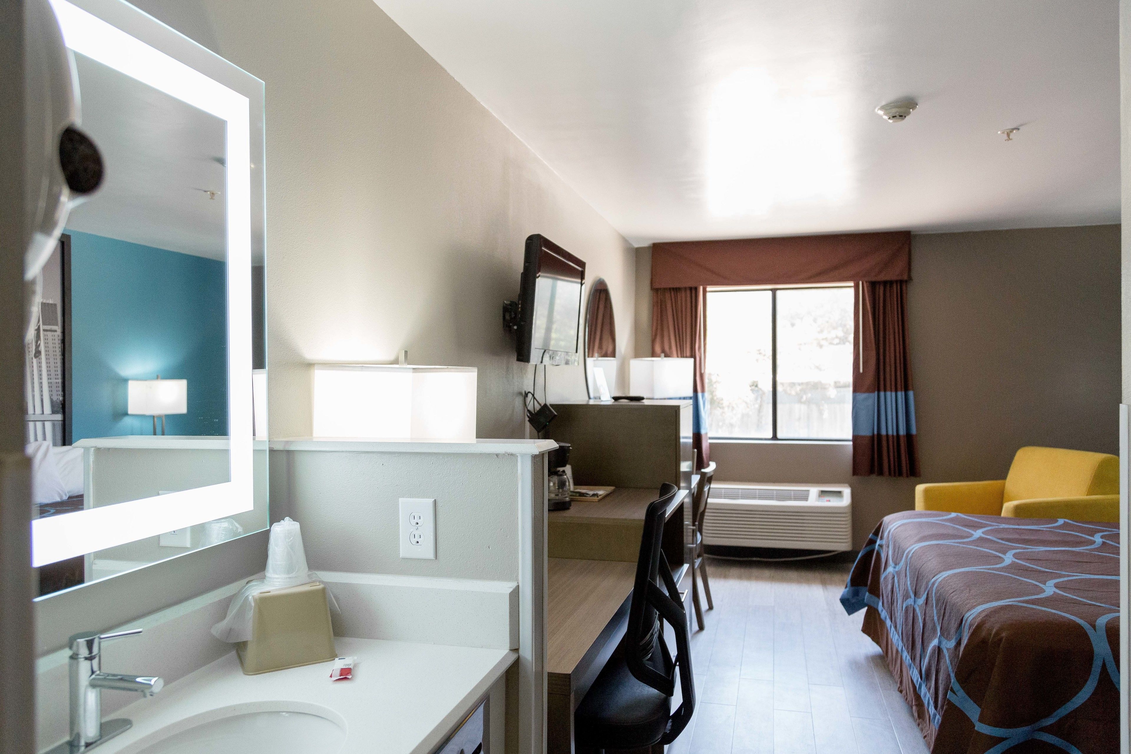 Habitación de hotel con escritorio, silla, cama y un espejo grande.