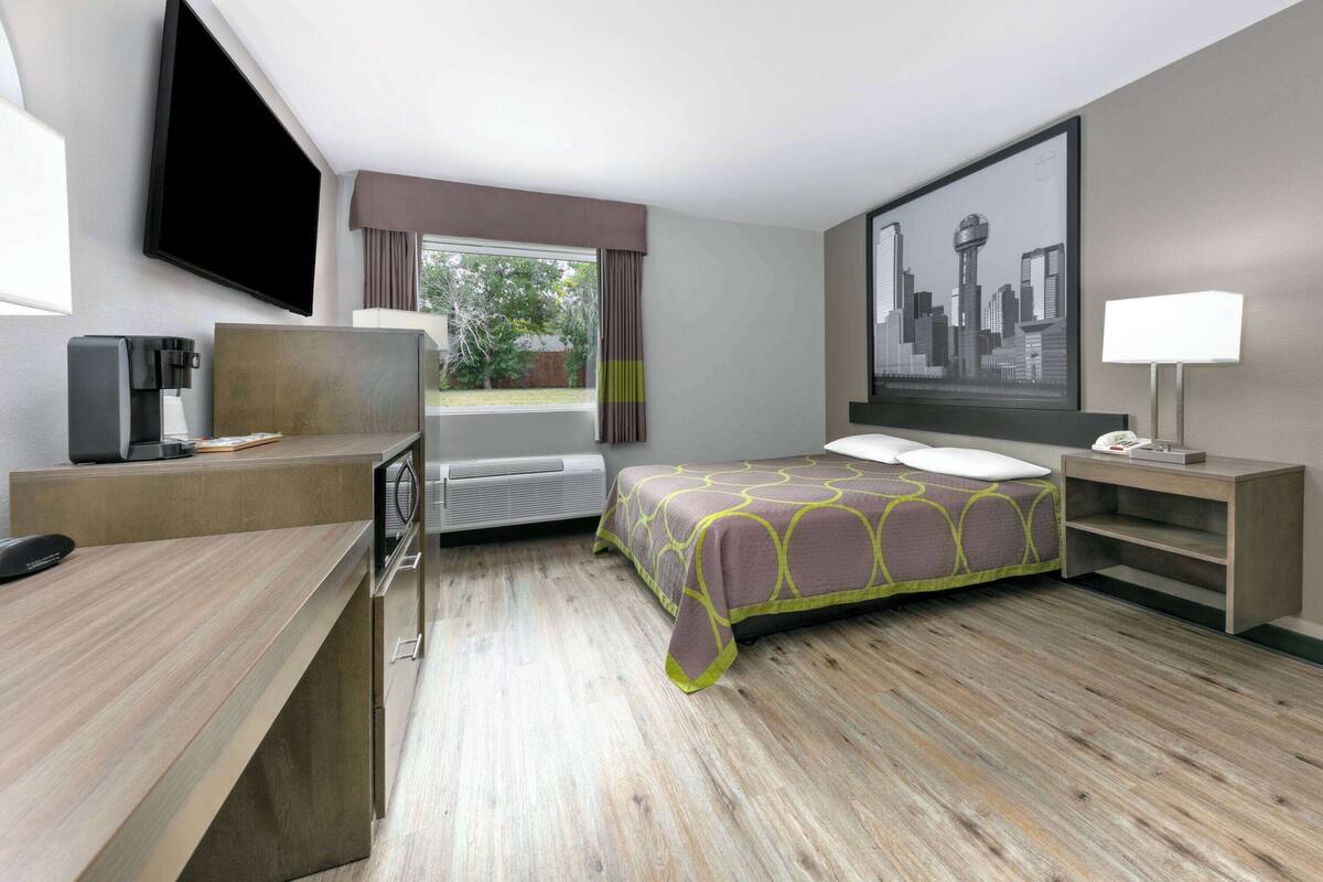 A hotel room with a bed, desk, and a large window.