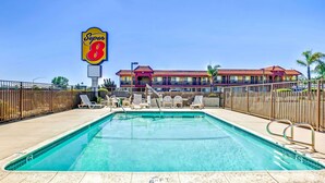 A hotel with a swimming pool, lounge chairs, and a Super 8 sign.
