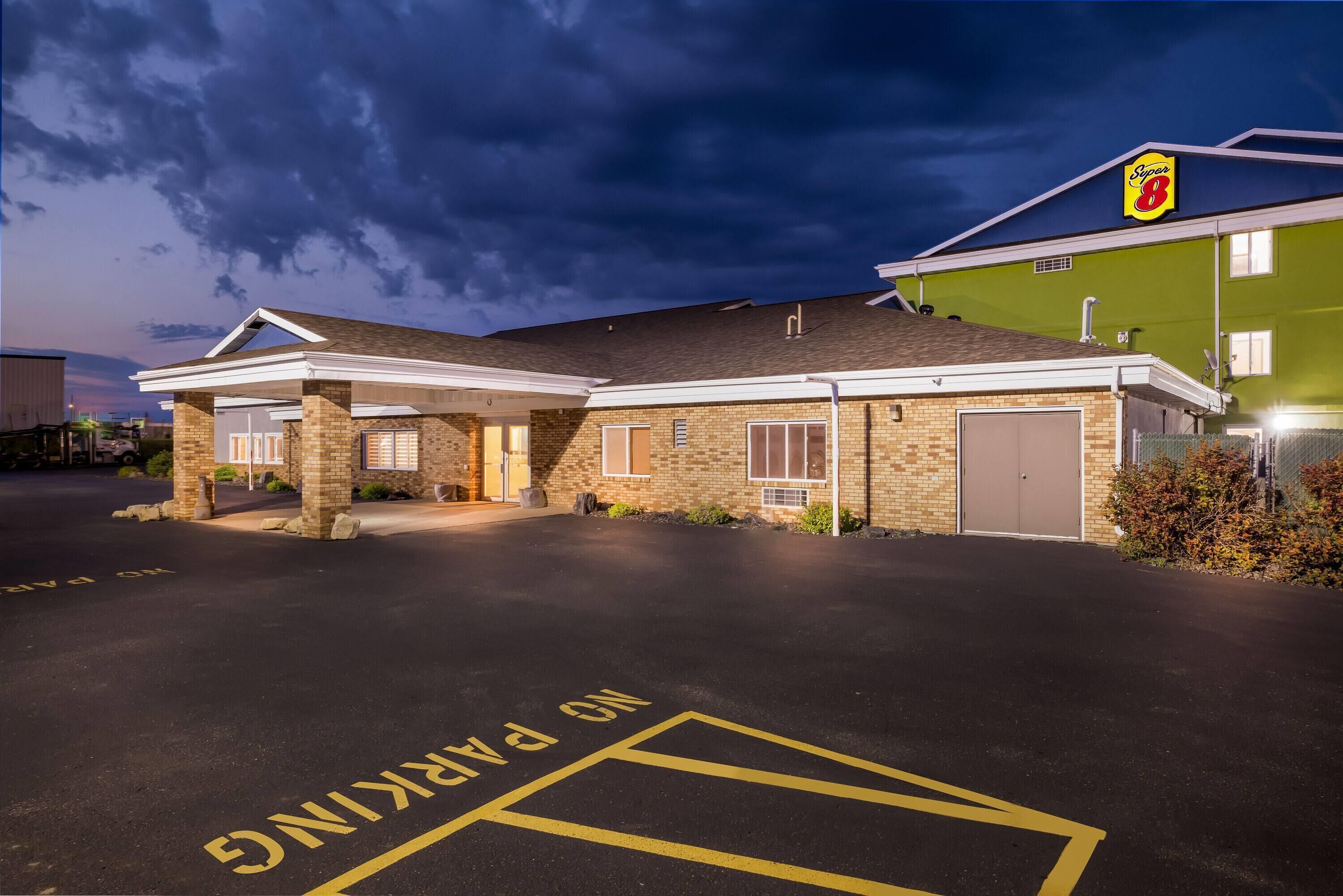 A hotel with a brick facade, a covered entrance, and a parking area marked "No Parking."