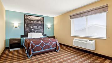Ein Hotelzimmer mit Bett, Nachttischen, einer Wand-Klimaanlage und einem großen Fenster.
