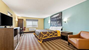 A hotel room with a bed, a desk, a TV, a chair, and a painting on the wall.