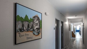 A hallway with a framed artwork on the wall, a light switch, and a wooden bench. - Rodeway Inn & Suites near Outlet Mall - Asheville (Asheville)