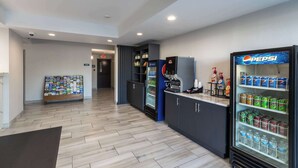 A hotel lobby with a Pepsi refrigerator, a Coca-Cola refrigerator, and a vending machine. - Rodeway Inn & Suites near Outlet Mall - Asheville (Asheville)