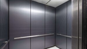 A modern elevator with metallic walls and a wooden floor. - Rodeway Inn & Suites near Outlet Mall - Asheville (Asheville)