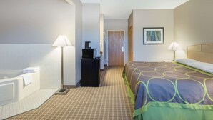 A hotel room with a bed, a desk, a lamp, a bathroom with a bathtub, and a door leading to another room. - Super 8 by Wyndham Carroll/East (Carroll)