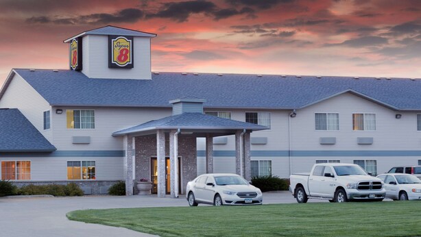 A hotel with a covered entrance, multiple parking spaces, and a clear sky. - Super 8 by Wyndham Carroll/East (Carroll)