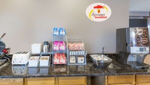 A breakfast station with toasters, coffee makers, and various food items. - Super 8 by Wyndham Carroll/East (Carroll)