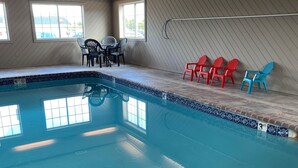 An indoor swimming pool with a tiled edge, a few chairs, and a bench. - Super 8 by Wyndham Carroll/East (Carroll)