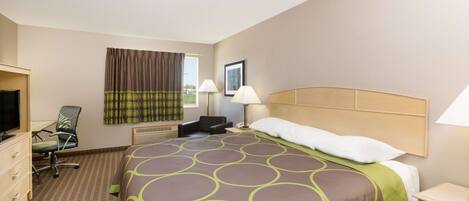 A hotel room with a large bed, a desk with a chair, a television, and a window with curtains.