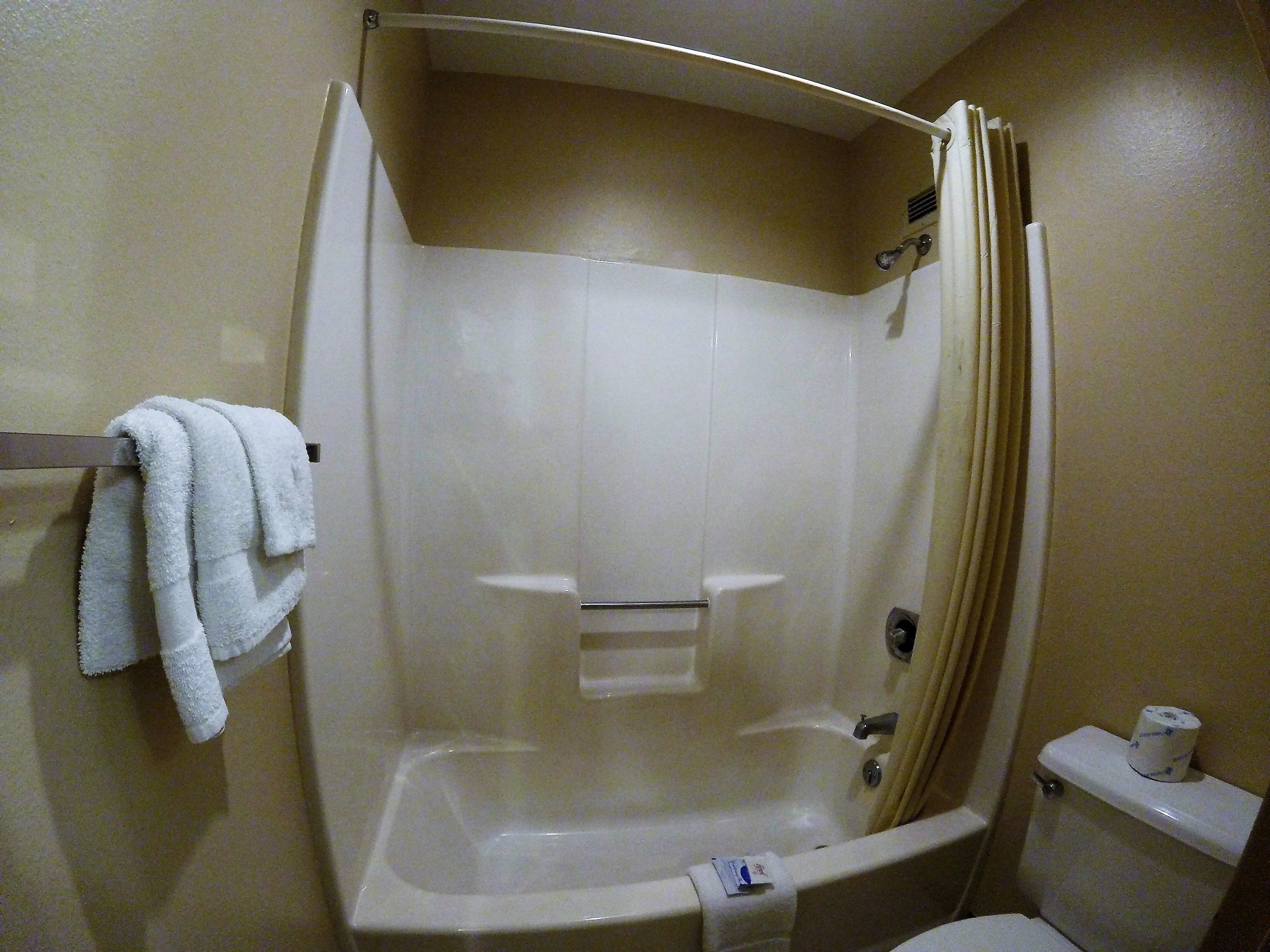 Un bagno con una vasca, un water e un portasciugamani con asciugamani.