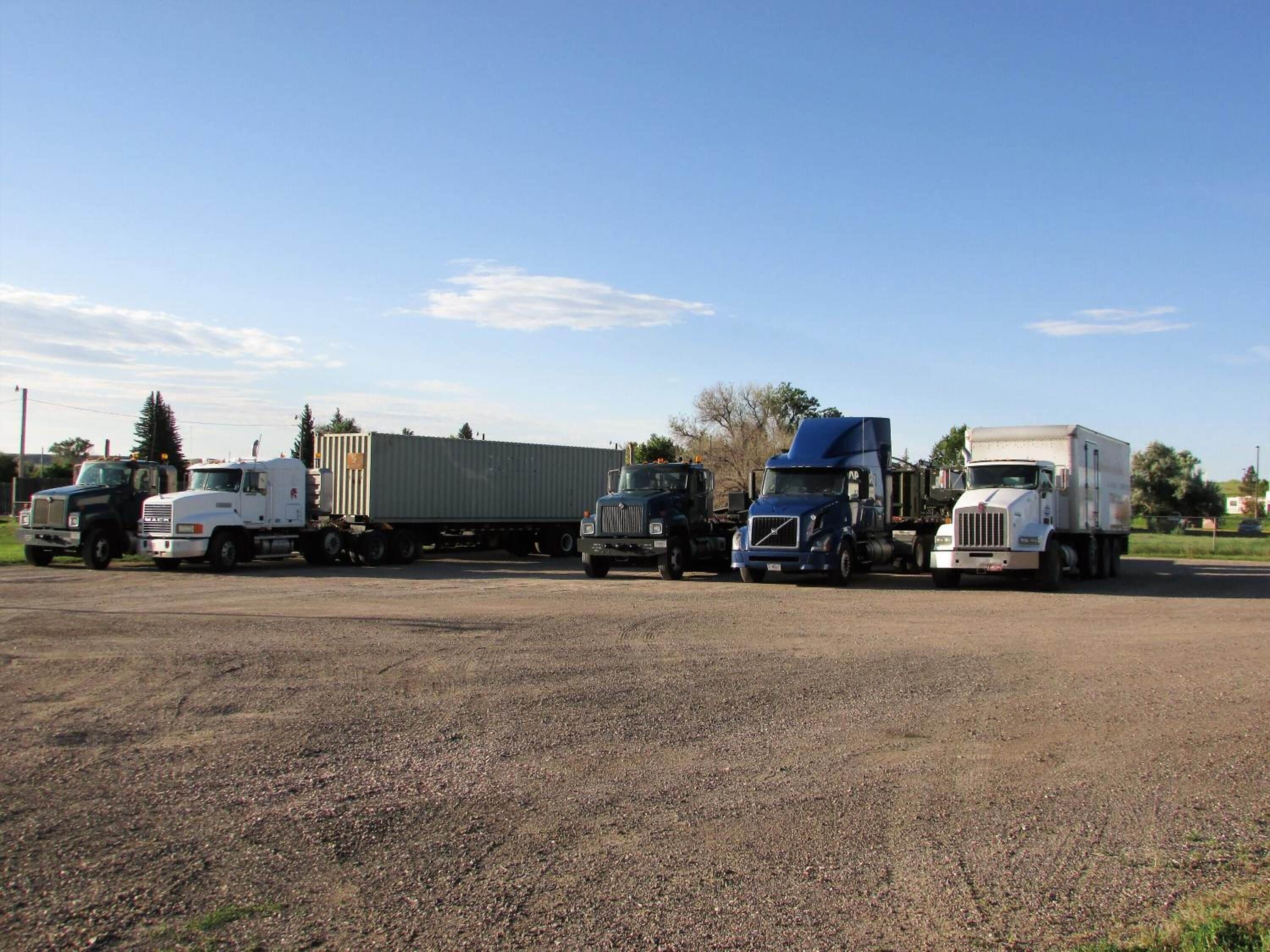 A parking lot with several trucks and a trailer.