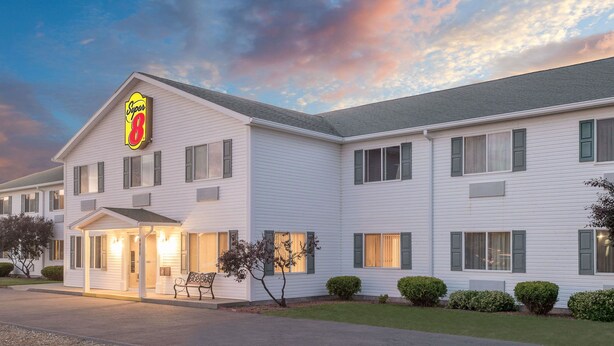 Un motel Super 8 con fachada blanca, múltiples ventanas y una entrada bien iluminada.