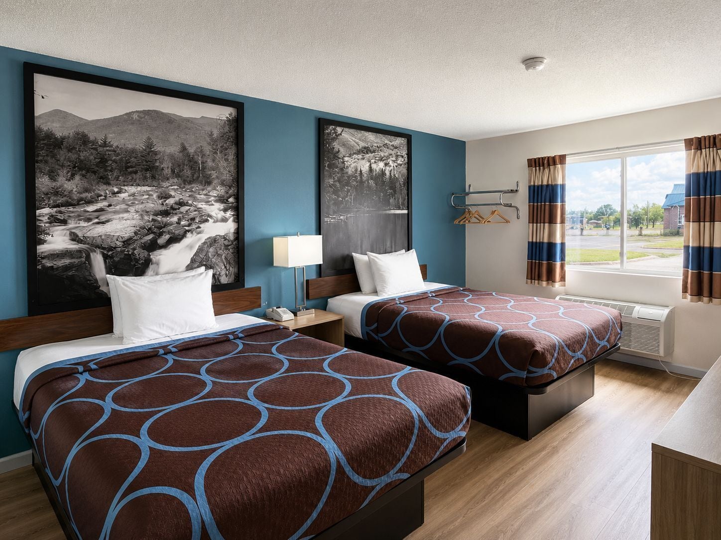 Una habitación de hotel con dos camas, una ventana con cortinas y obras de arte en las paredes.