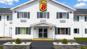 Un hôtel à deux étages, reconnaissable à son grand panneau « Super 8 », doté d’une entrée centrale et d’un parking avec des places délimitées.