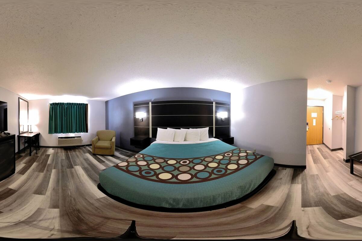 A bedroom with a curved bed, a desk, a chair, and a TV.