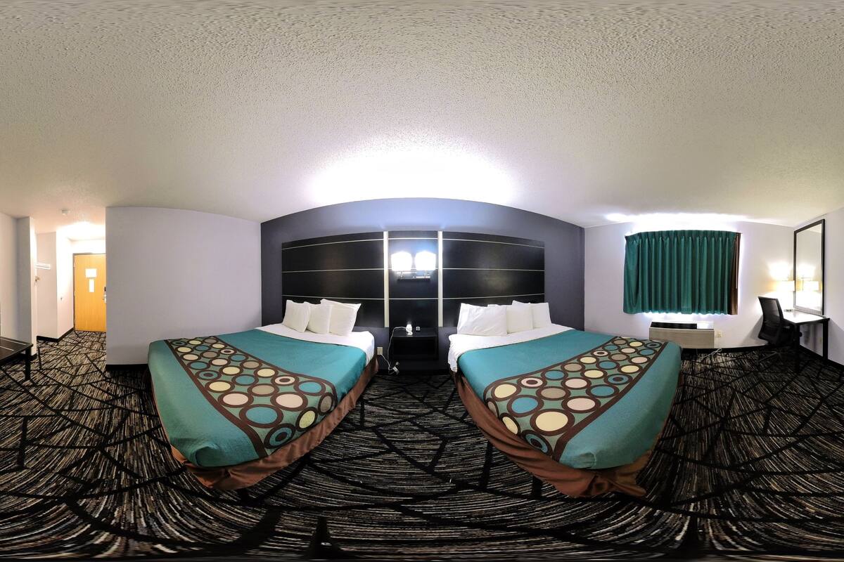 A hotel room with two beds, a desk, and a chair.
