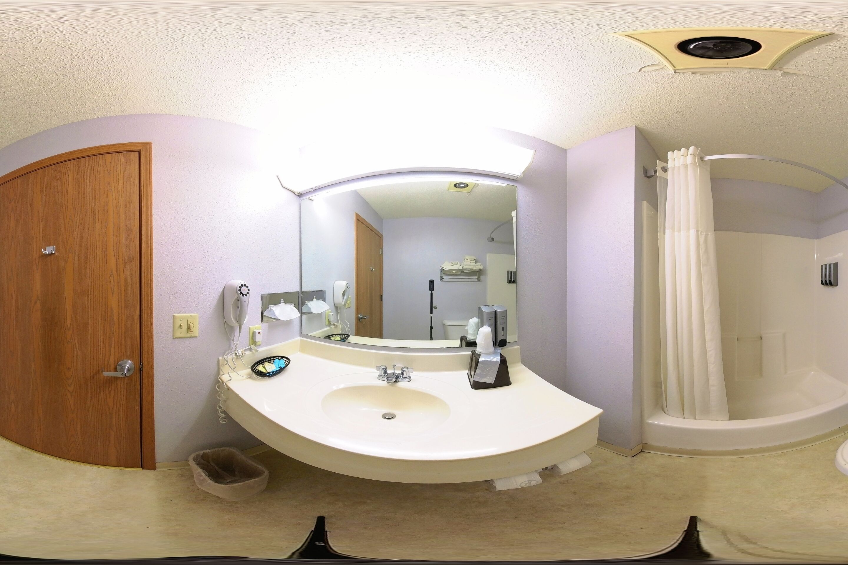 A bathroom with a sink, mirror, and shower.