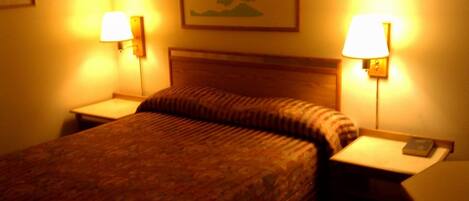 A hotel room with a bed, two bedside tables, and two wall-mounted lamps.
