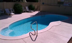 Una piscina amb una escala metàl·lica, gandules i un bou salvavides.