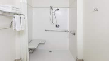 A white shower stall with a handheld showerhead, a handheld shower attachment, and a grab bar.