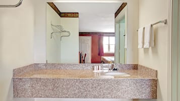 Une salle de bain avec un comptoir en granit, un miroir et un porte-serviettes.